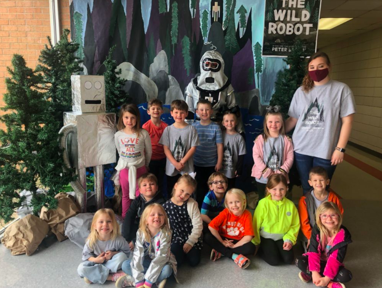 A classroom of students poses in front of a decorative display